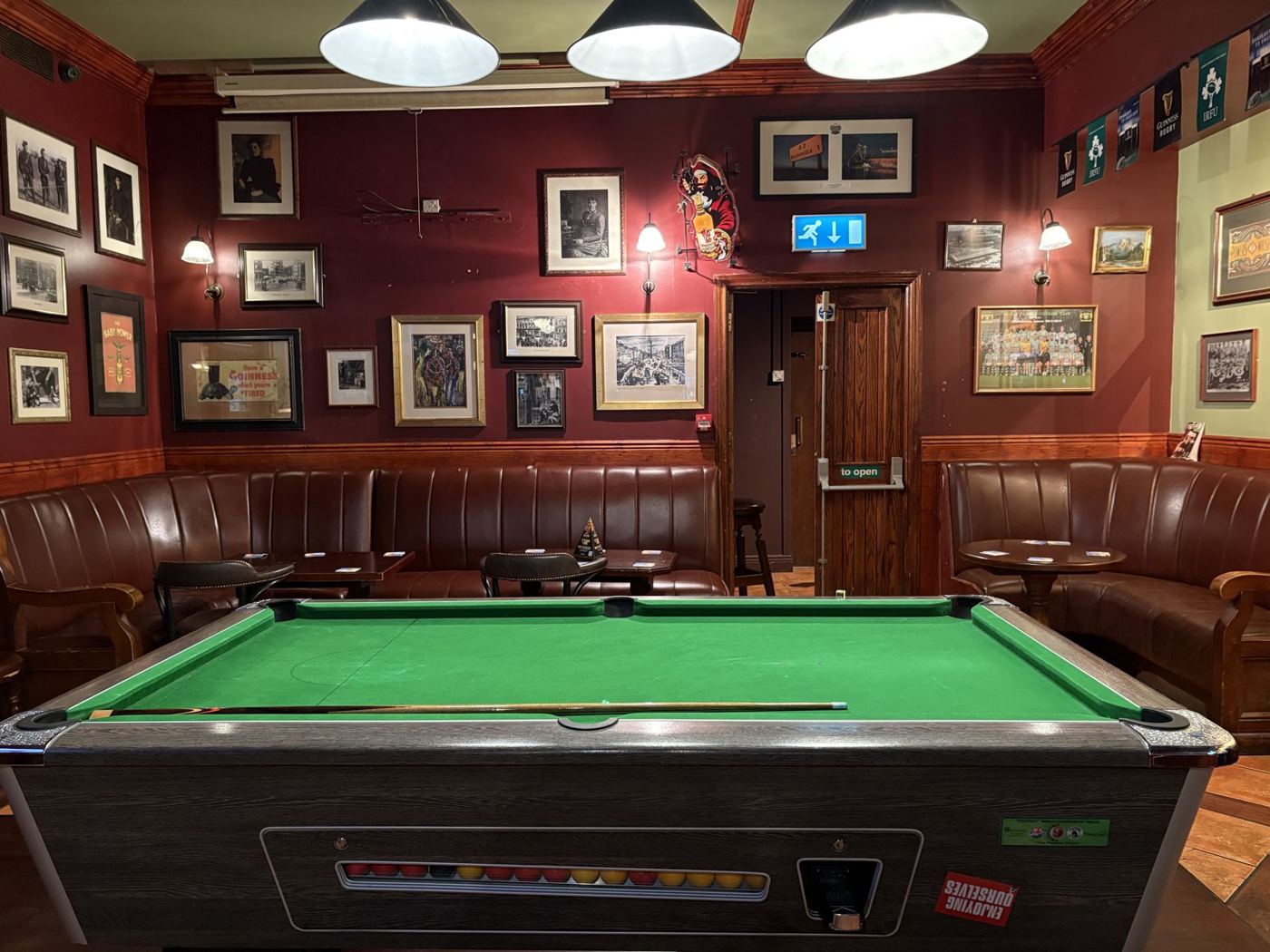 The pool room with red walls and framed pictures
